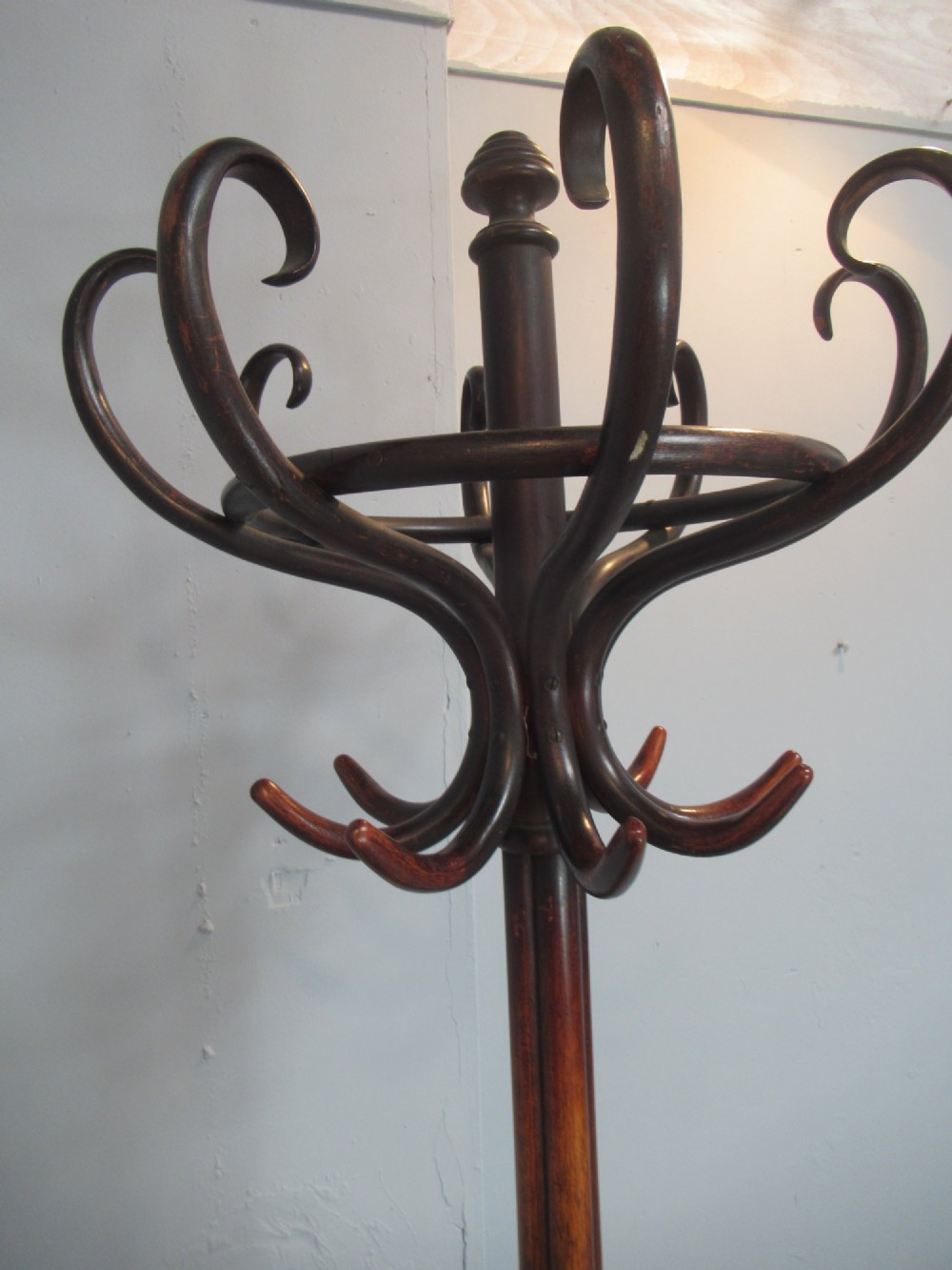 A dark brown bentwood hat and coat stand featuring multiple curved upper hooks, a central turned pole, a lower umbrella ring, and splayed legs. View VII
