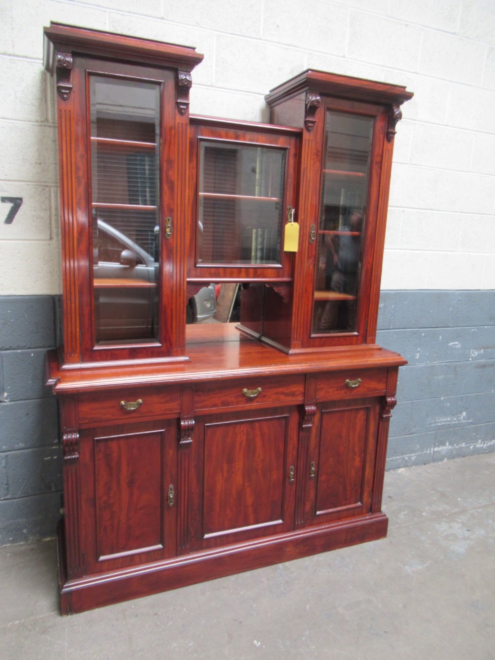 Late Victorian mahogany bookcase featuring glazed upper cabinet sections, carved corbels, fluted pilasters, drawers, and lower panelled doors.