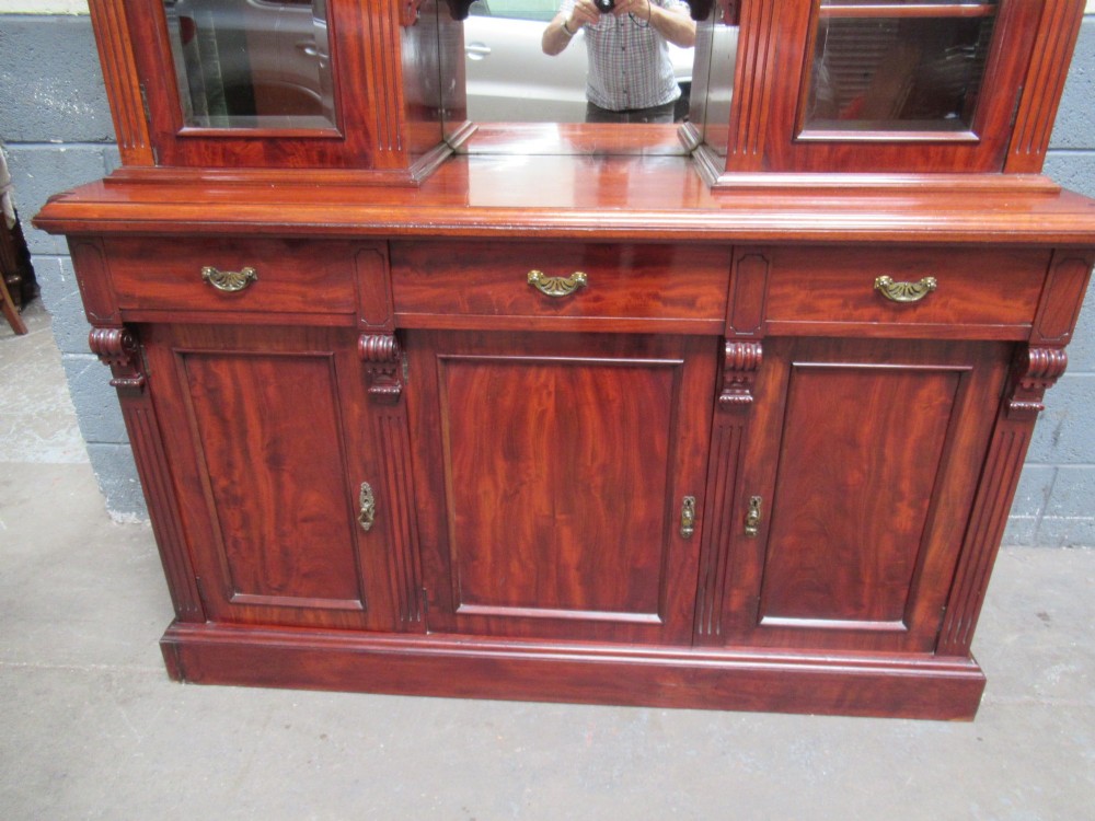 Late Victorian mahogany bookcase featuring glazed upper cabinet sections, carved corbels, fluted pilasters, drawers, and lower panelled doors. View V