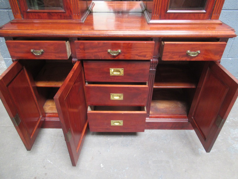 Late Victorian mahogany bookcase featuring glazed upper cabinet sections, carved corbels, fluted pilasters, drawers, and lower panelled doors. View VI