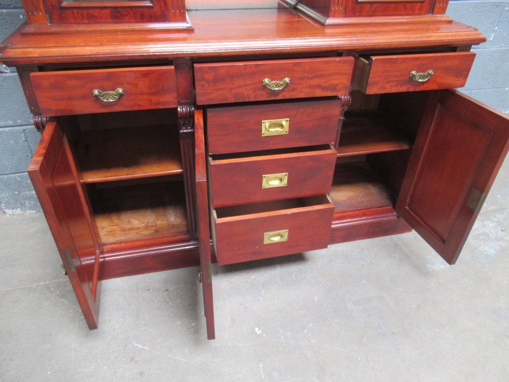 Late Victorian mahogany bookcase featuring glazed upper cabinet sections, carved corbels, fluted pilasters, drawers, and lower panelled doors. View VII