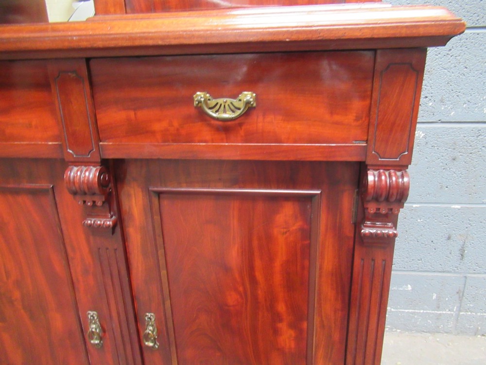 Late Victorian mahogany bookcase featuring glazed upper cabinet sections, carved corbels, fluted pilasters, drawers, and lower panelled doors. View IX