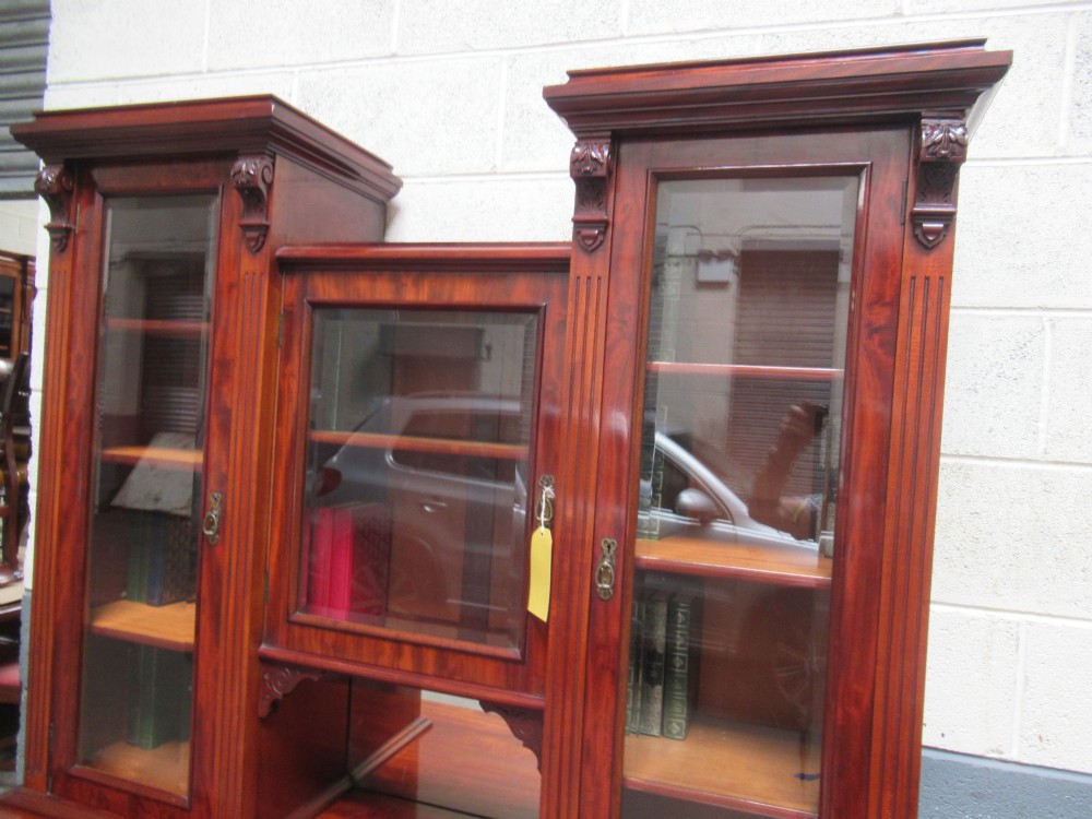 Late Victorian mahogany bookcase featuring glazed upper cabinet sections, carved corbels, fluted pilasters, drawers, and lower panelled doors. View X