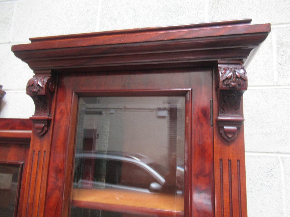 Late Victorian mahogany bookcase featuring glazed upper cabinet sections, carved corbels, fluted pilasters, drawers, and lower panelled doors. View XI