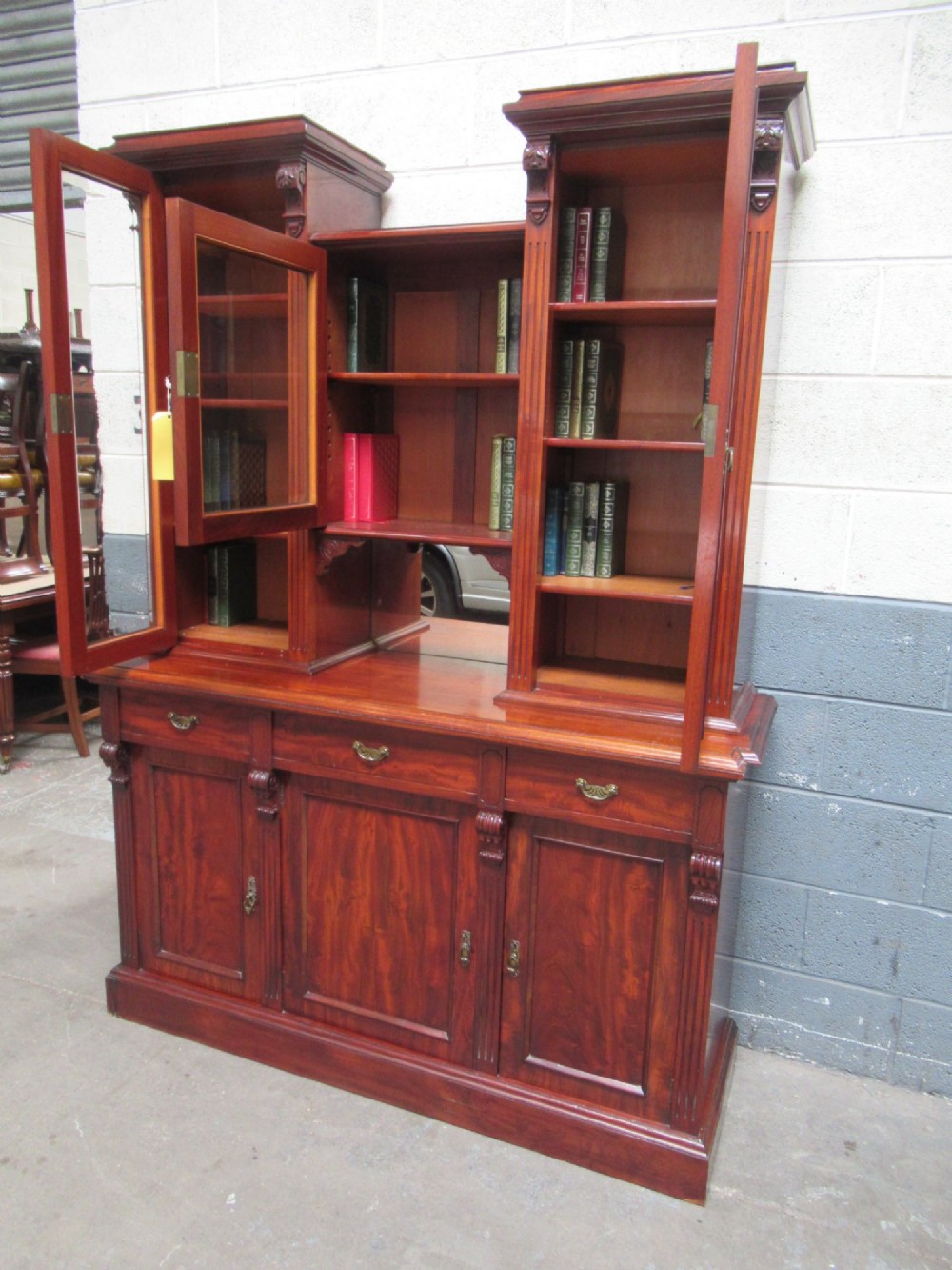 Late Victorian mahogany bookcase featuring glazed upper cabinet sections, carved corbels, fluted pilasters, drawers, and lower panelled doors. View XII