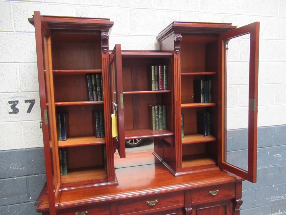 Late Victorian mahogany bookcase featuring glazed upper cabinet sections, carved corbels, fluted pilasters, drawers, and lower panelled doors. View XIII