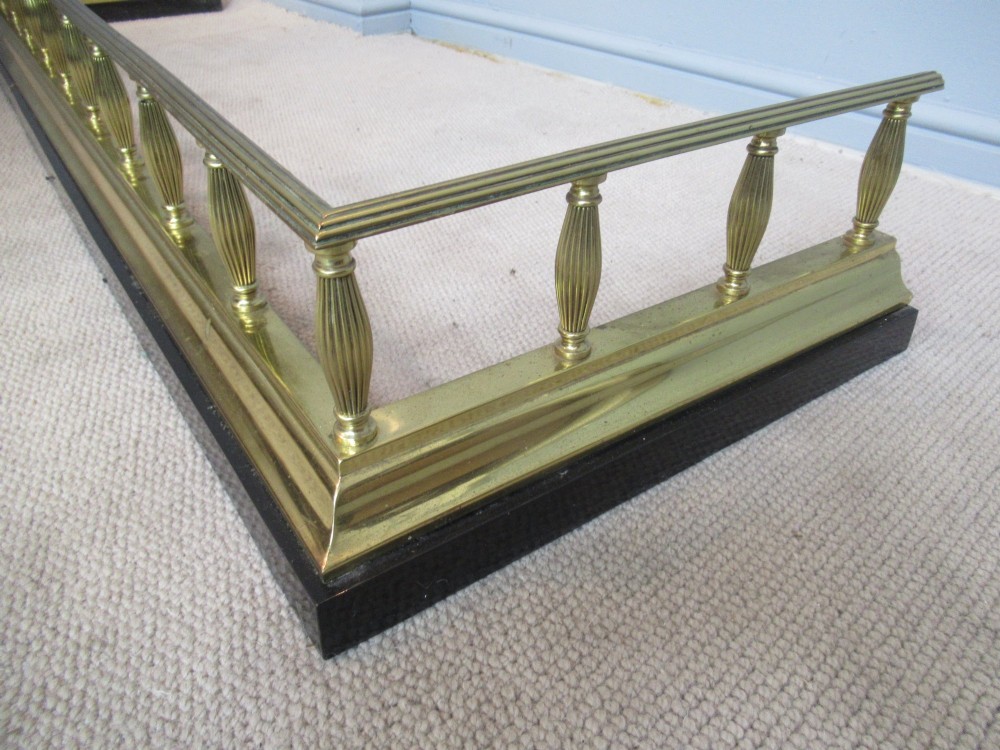 A late Victorian brass and iron fire fender featuring a polished brass top rail with fluted baluster uprights on a heavy black base. View III