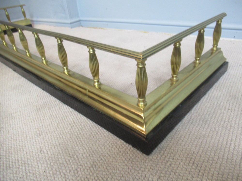 A late Victorian brass and iron fire fender featuring a polished brass top rail with fluted baluster uprights on a heavy black base. View IV