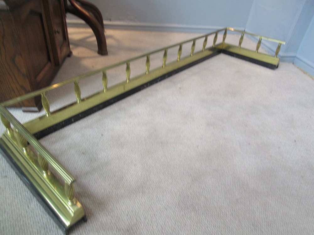 A late Victorian brass and iron fire fender featuring a polished brass top rail with fluted baluster uprights on a heavy black base. View V