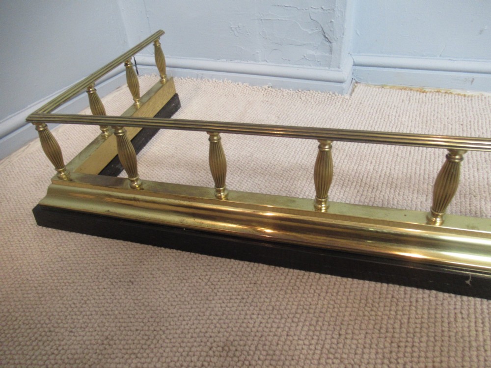 A late Victorian brass and iron fire fender featuring a polished brass top rail with fluted baluster uprights on a heavy black base. View VII