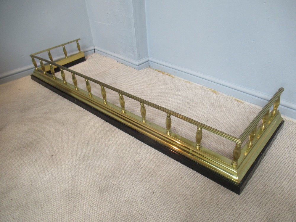 A late Victorian brass and iron fire fender featuring a polished brass top rail with fluted baluster uprights on a heavy black base. View VIII