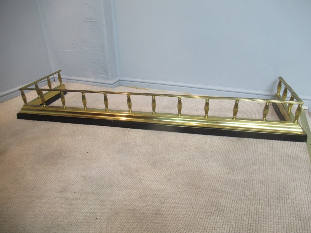A late Victorian brass and iron fire fender featuring a polished brass top rail with fluted baluster uprights on a heavy black base. View IX