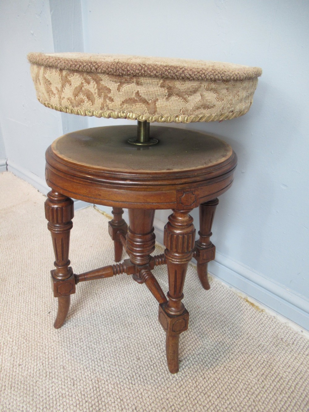 A Victorian walnut revolving piano stool featuring fluted carved legs, cross-stretchers, and a circular padded tapestry upholstered seat. View VIII