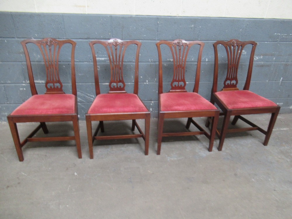 A set of four Edwardian mahogany dining chairs with carved pierced back splats and red velvet upholstered seats.