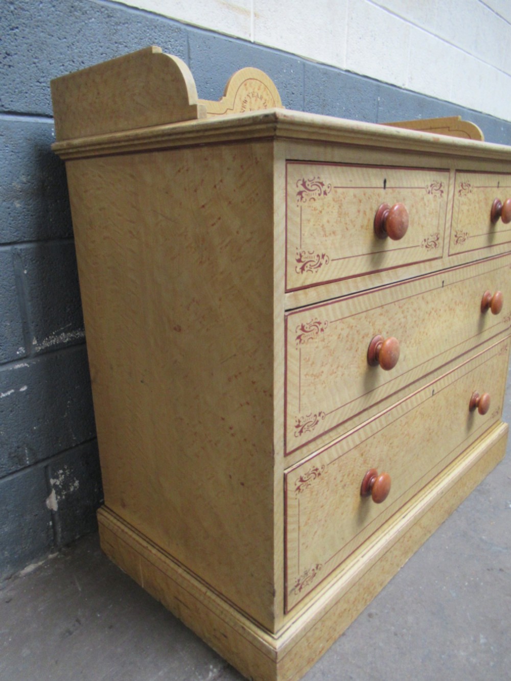 A Victorian painted pine chest of drawers with two short over two long drawers, decorated with scumbled graining, red stencilled borders, turned wooden knobs, and an upstand inscribed New Year Day 1894. View VII