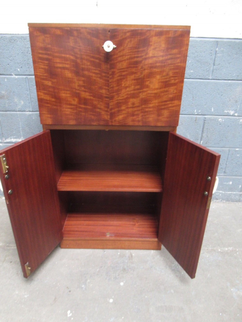 An Art Deco writing bureau in dark brown veneered wood featuring an open fall-front flap that reveals a light-coloured fitted interior with drawers and pigeonholes. View V