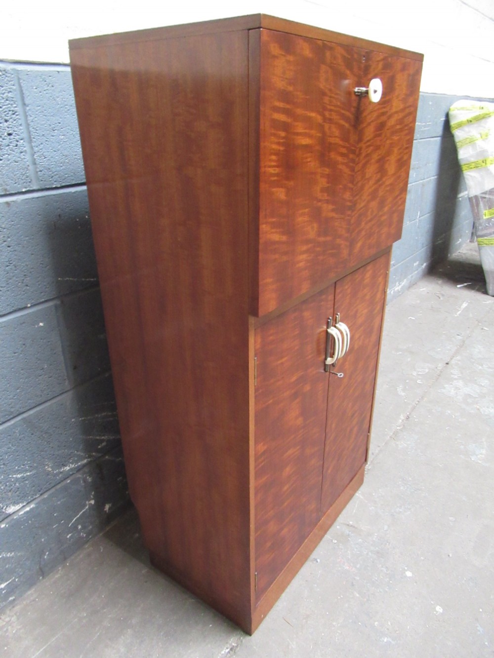 An Art Deco writing bureau in dark brown veneered wood featuring an open fall-front flap that reveals a light-coloured fitted interior with drawers and pigeonholes. View VI
