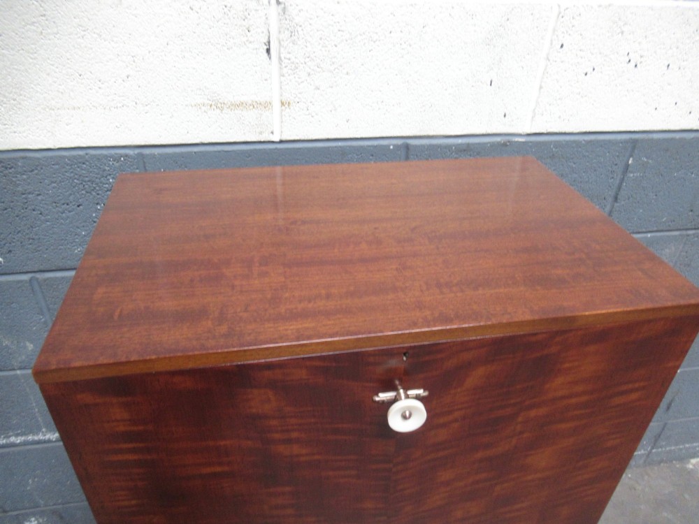 An Art Deco writing bureau in dark brown veneered wood featuring an open fall-front flap that reveals a light-coloured fitted interior with drawers and pigeonholes. View VIII