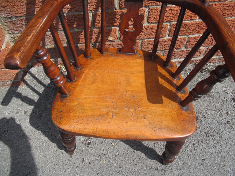 A warm brown wooden childs Windsor armchair with a hoop back, central pierced splat, turned legs, and a solid shaped seat. View V