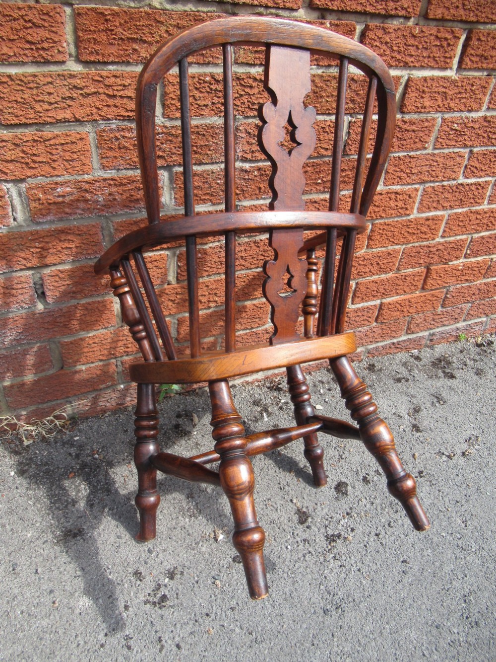 A warm brown wooden childs Windsor armchair with a hoop back, central pierced splat, turned legs, and a solid shaped seat. View VIII