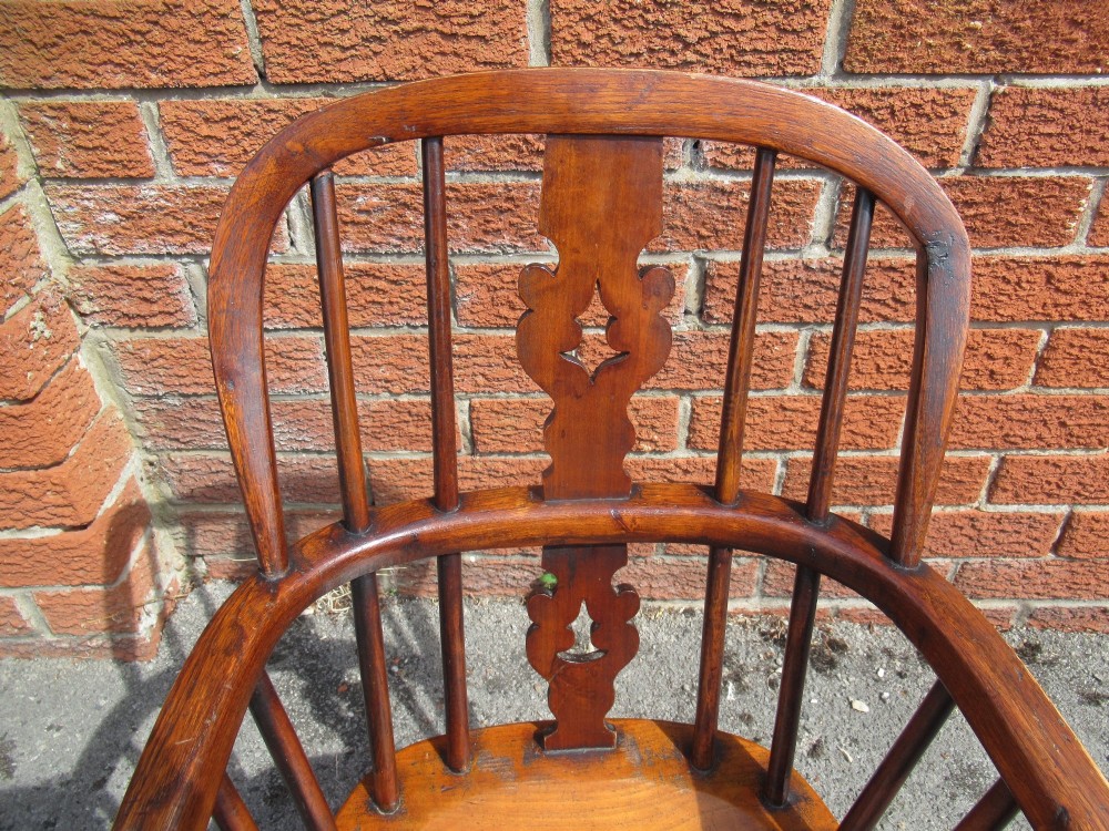A warm brown wooden childs Windsor armchair with a hoop back, central pierced splat, turned legs, and a solid shaped seat. View IX
