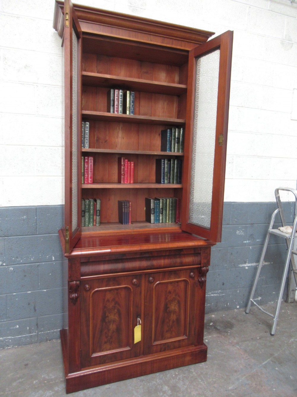 A tall 19th-century Victorian mahogany glazed bookcase featuring a two-door upper section above a lower cupboard base with carved corbels. View II