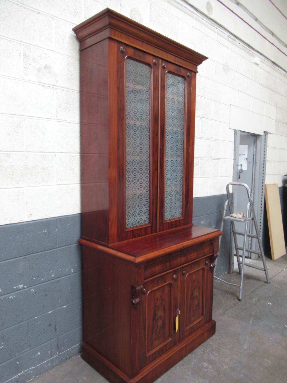 A tall 19th-century Victorian mahogany glazed bookcase featuring a two-door upper section above a lower cupboard base with carved corbels. View III