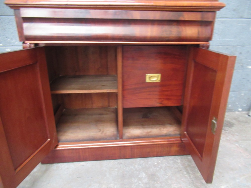 A tall 19th-century Victorian mahogany glazed bookcase featuring a two-door upper section above a lower cupboard base with carved corbels. View VI
