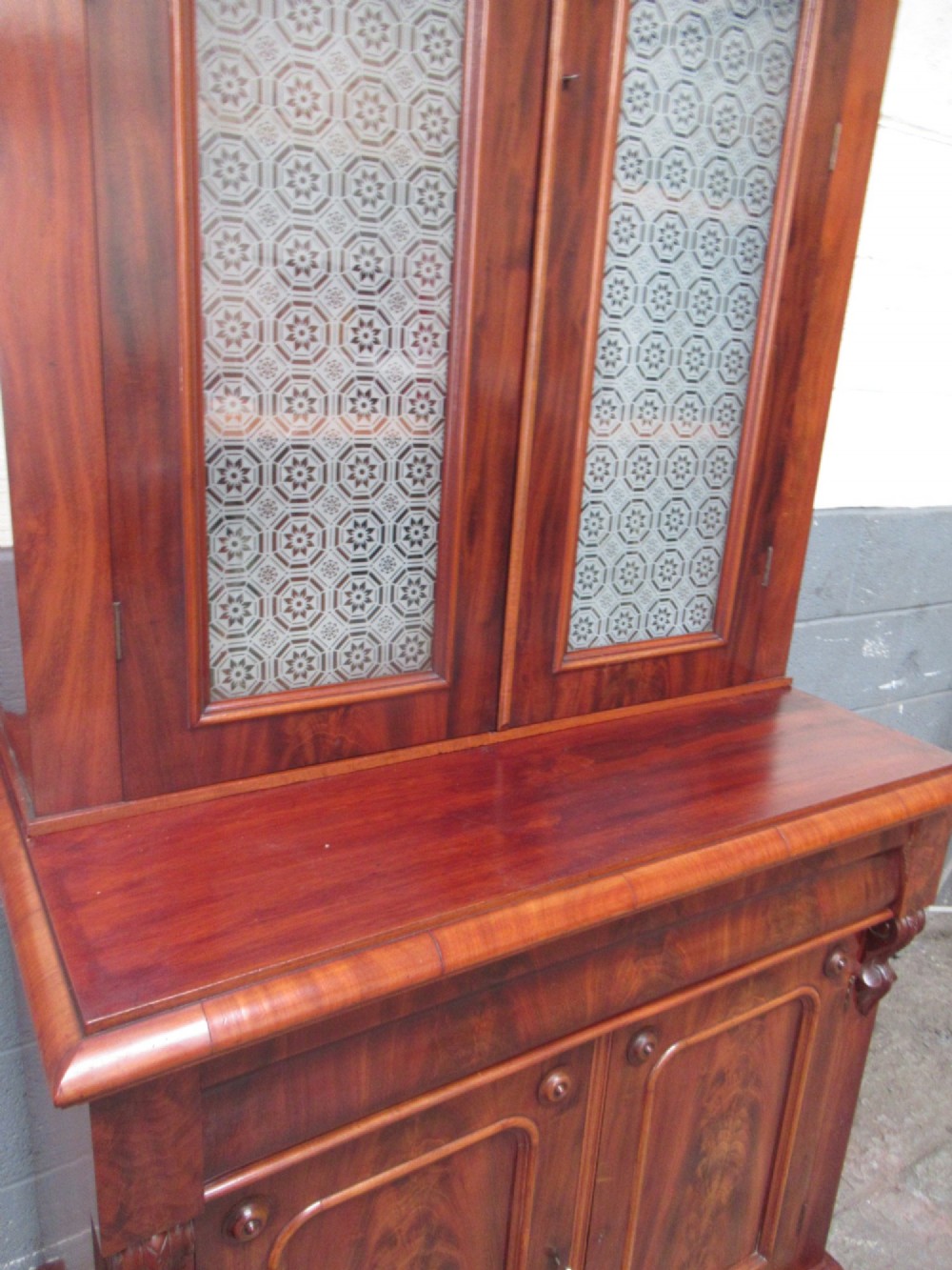 A tall 19th-century Victorian mahogany glazed bookcase featuring a two-door upper section above a lower cupboard base with carved corbels. View XI
