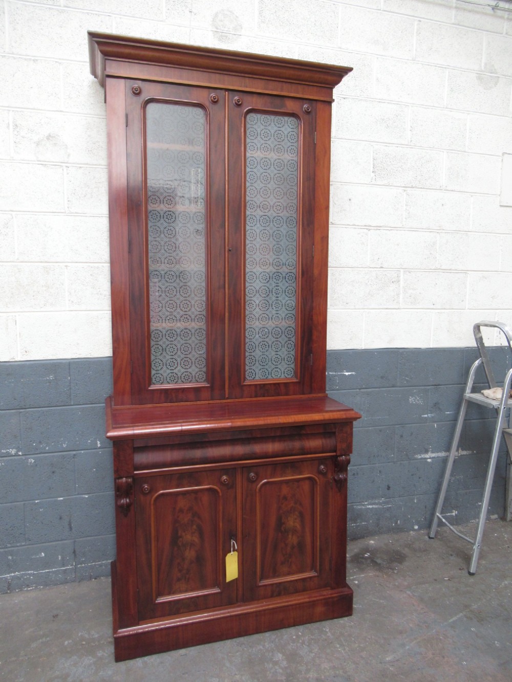 A tall 19th-century Victorian mahogany glazed bookcase featuring a two-door upper section above a lower cupboard base with carved corbels. View XII