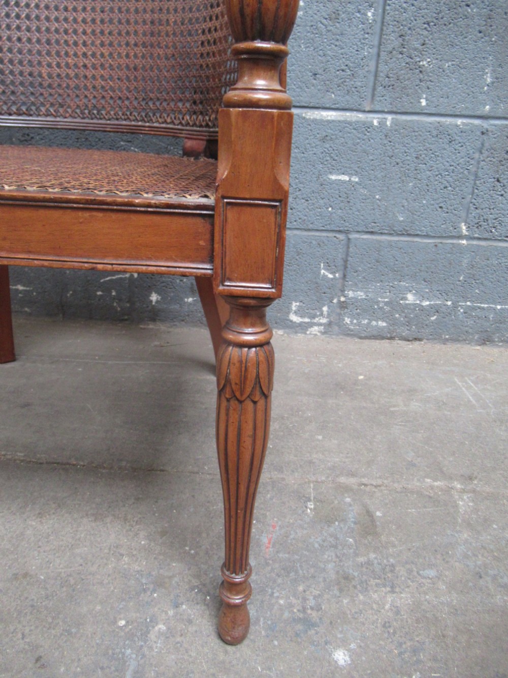 A mahogany tub-shaped armchair featuring a continuous woven cane backrest and seat with fluted front legs. View III