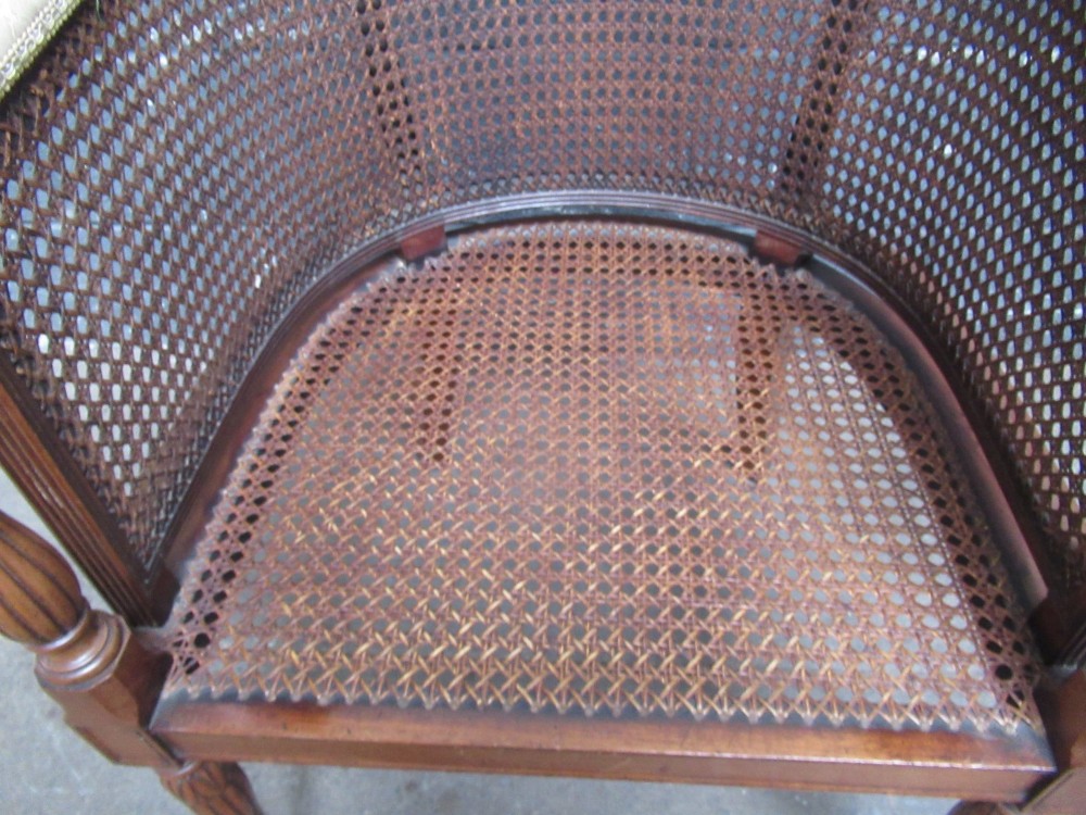 A mahogany tub-shaped armchair featuring a continuous woven cane backrest and seat with fluted front legs. View IV