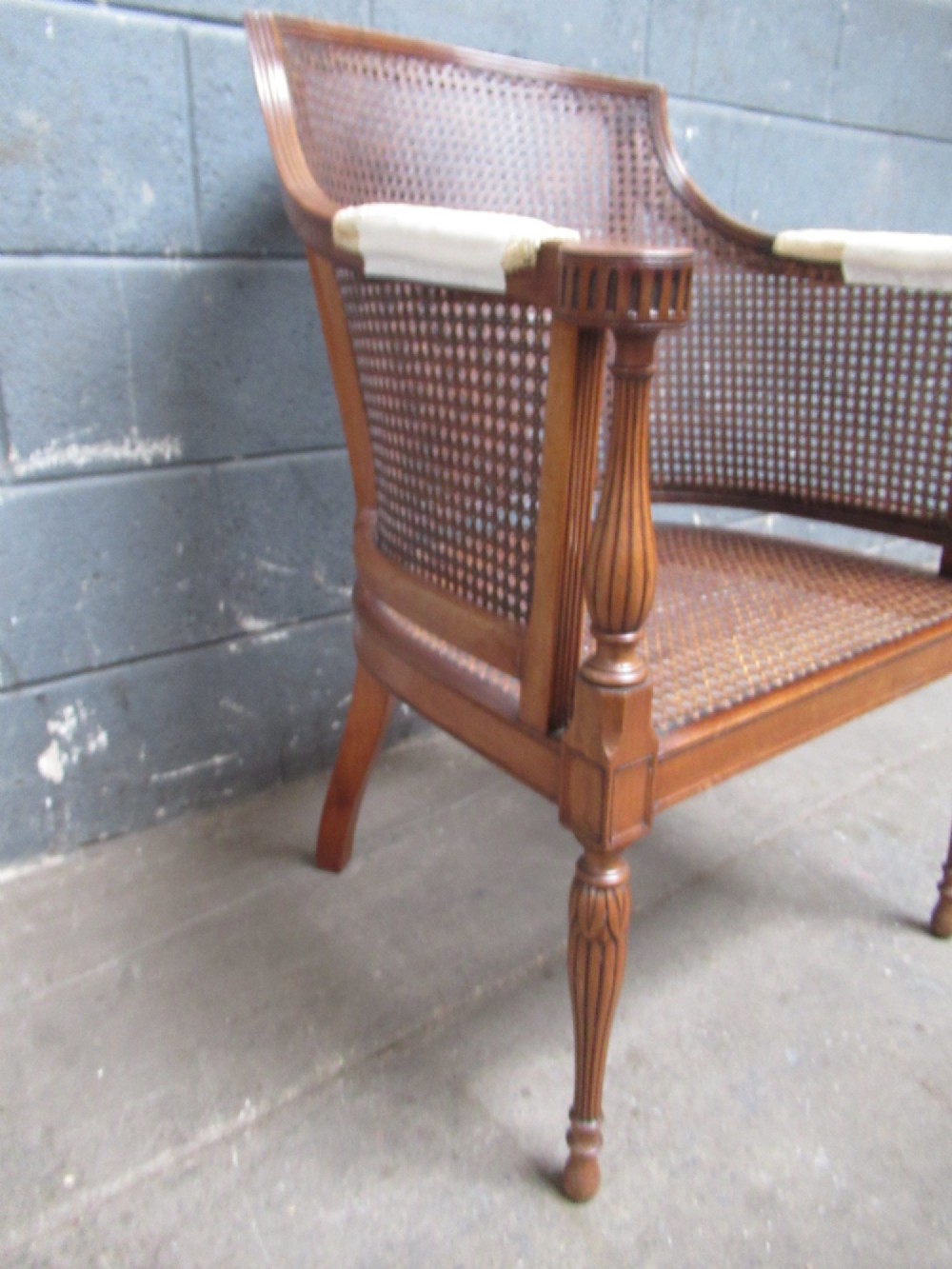 A mahogany tub-shaped armchair featuring a continuous woven cane backrest and seat with fluted front legs. View VI