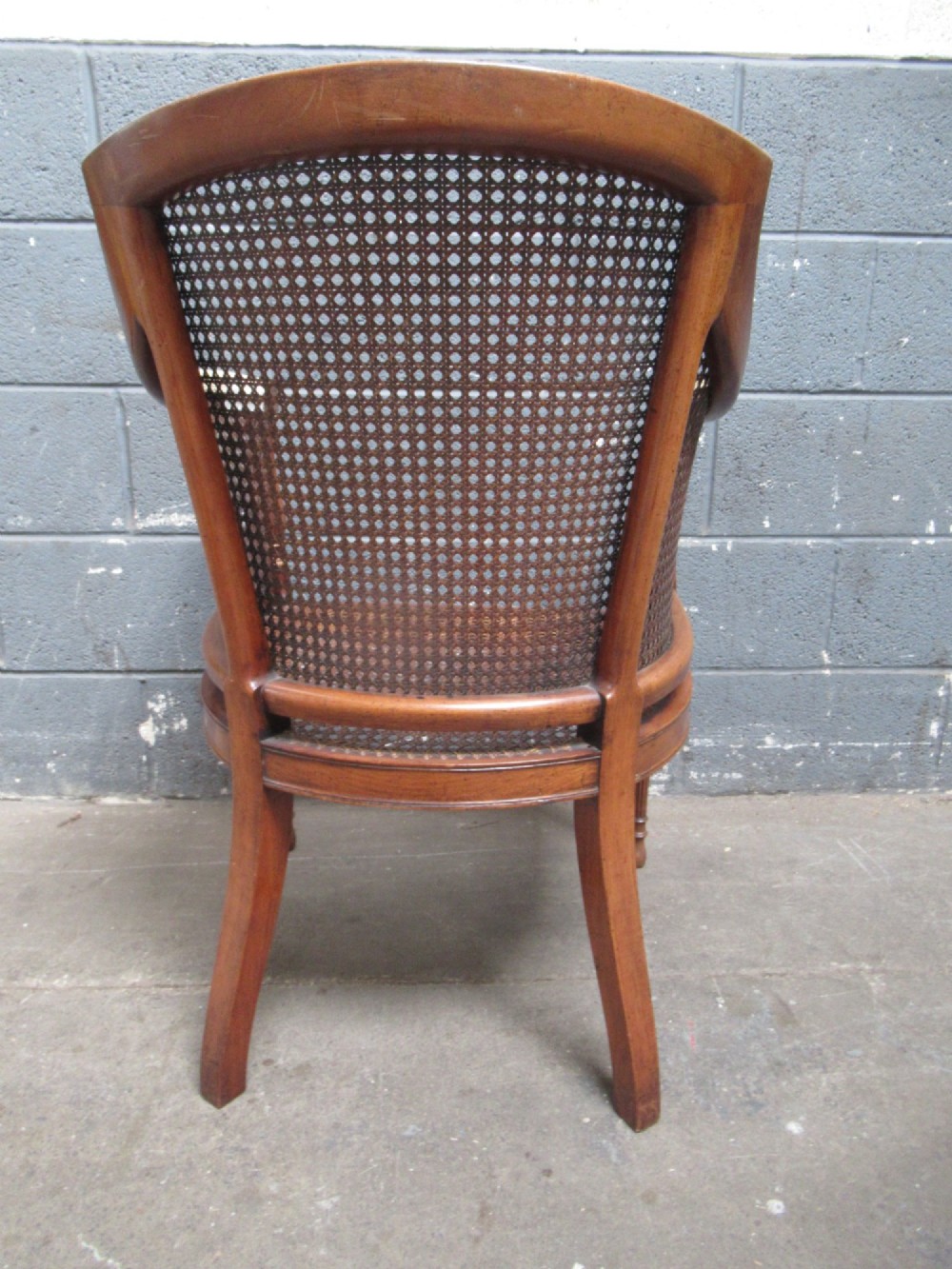 A mahogany tub-shaped armchair featuring a continuous woven cane backrest and seat with fluted front legs. View VIII