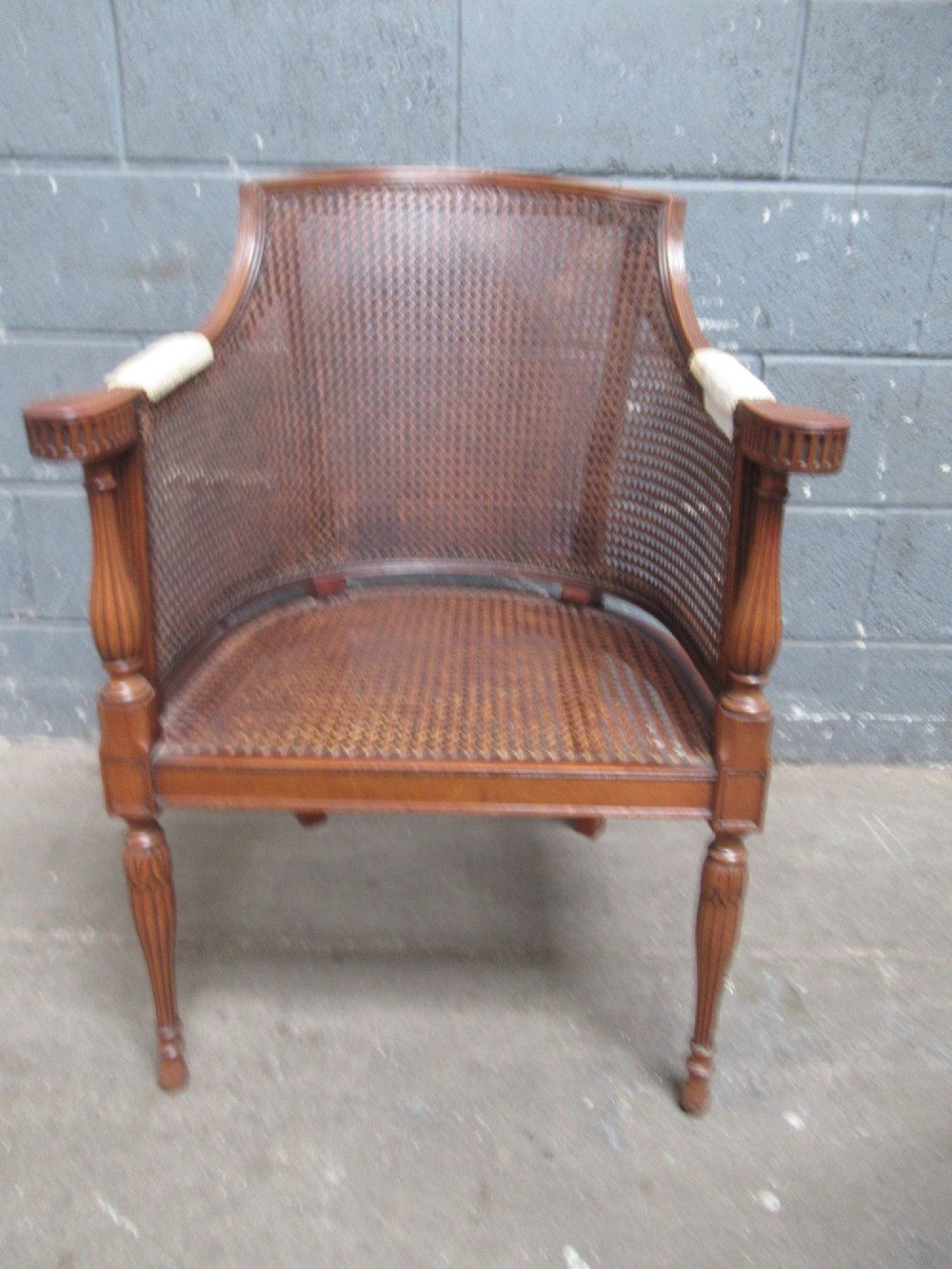 A mahogany tub-shaped armchair featuring a continuous woven cane backrest and seat with fluted front legs. View IX
