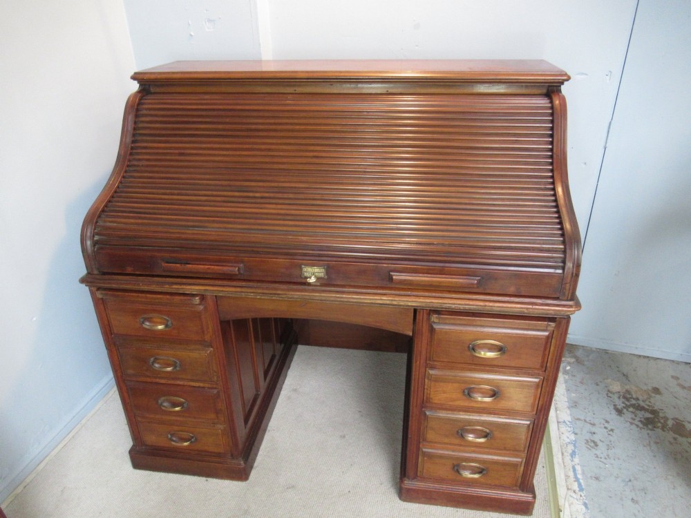 A large antique walnut roll-top desk featuring a slatted wooden tambour front over twin pedestals with eight brass-handled drawers. View II