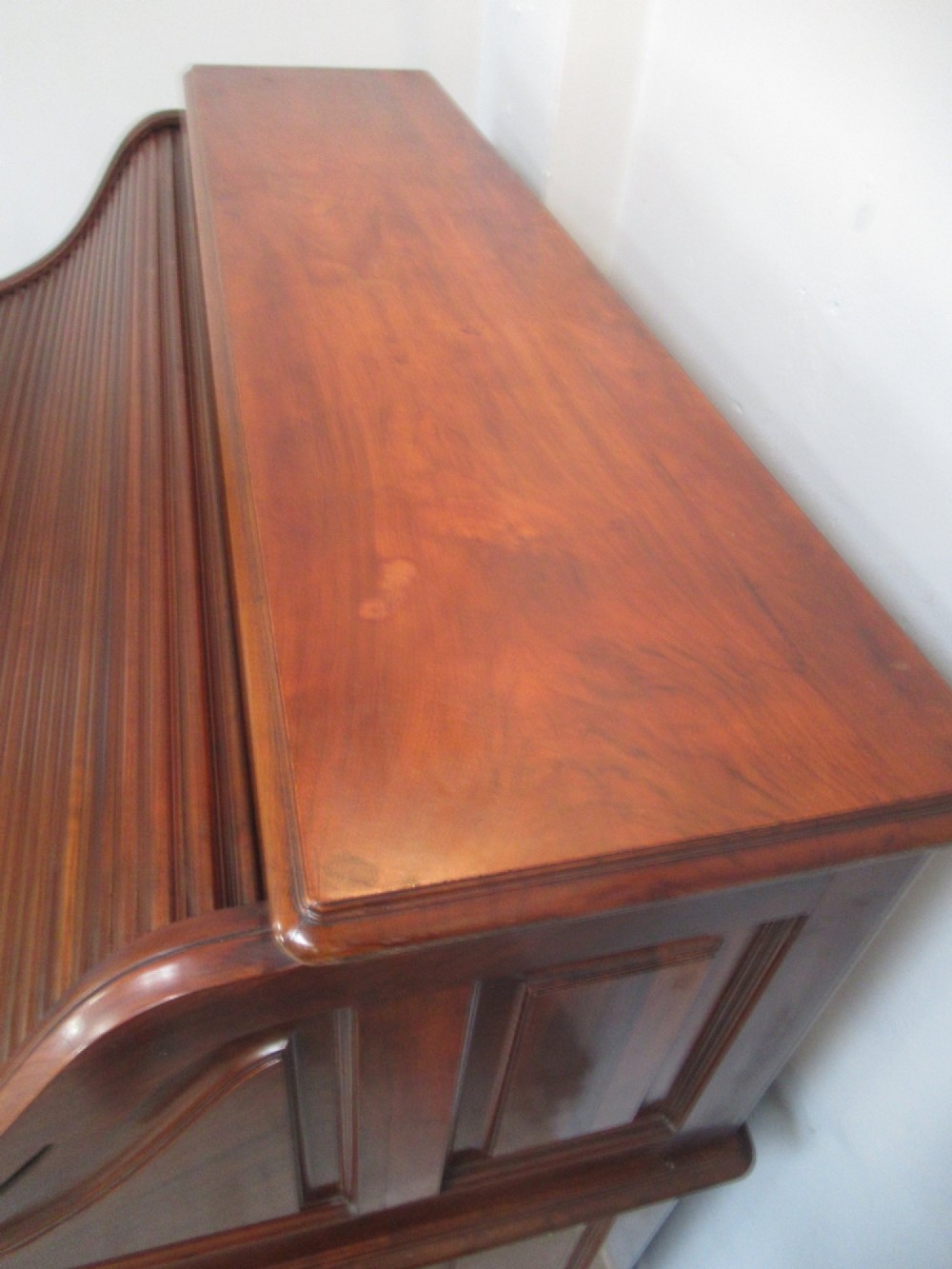 A large antique walnut roll-top desk featuring a slatted wooden tambour front over twin pedestals with eight brass-handled drawers. View VI