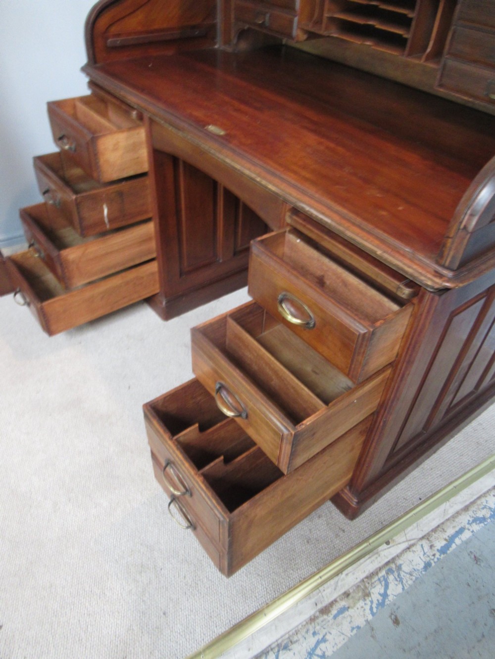 A large antique walnut roll-top desk featuring a slatted wooden tambour front over twin pedestals with eight brass-handled drawers. View IX