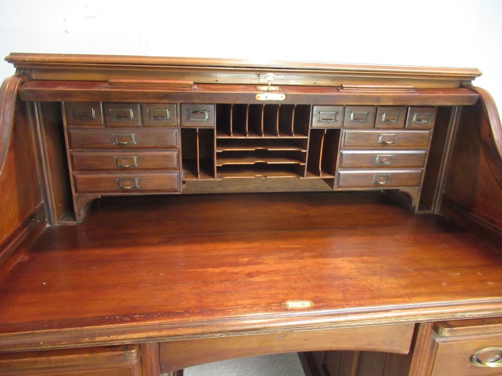A large antique walnut roll-top desk featuring a slatted wooden tambour front over twin pedestals with eight brass-handled drawers. View X
