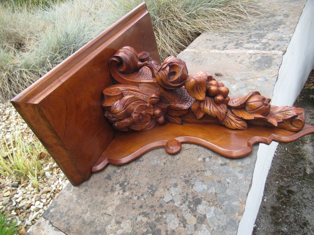 A carved Victorian walnut wall bracket featuring a flat top ledge supported by an ornate central motif of carved leaves, fruit, and scrollwork on a shaped backplate. View II