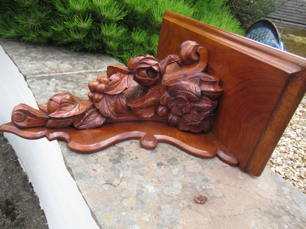 A carved Victorian walnut wall bracket featuring a flat top ledge supported by an ornate central motif of carved leaves, fruit, and scrollwork on a shaped backplate. View III