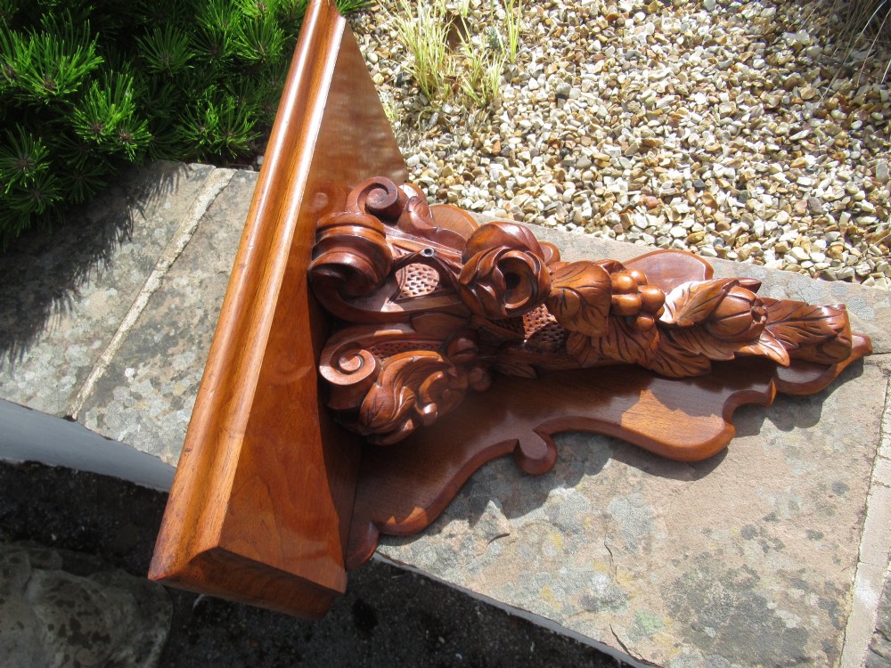 A carved Victorian walnut wall bracket featuring a flat top ledge supported by an ornate central motif of carved leaves, fruit, and scrollwork on a shaped backplate. View VII