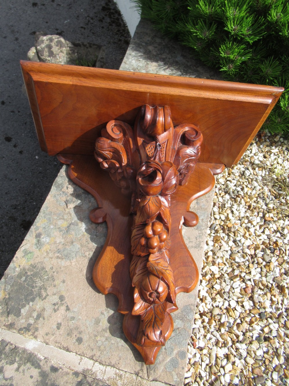 A carved Victorian walnut wall bracket featuring a flat top ledge supported by an ornate central motif of carved leaves, fruit, and scrollwork on a shaped backplate. View VIII