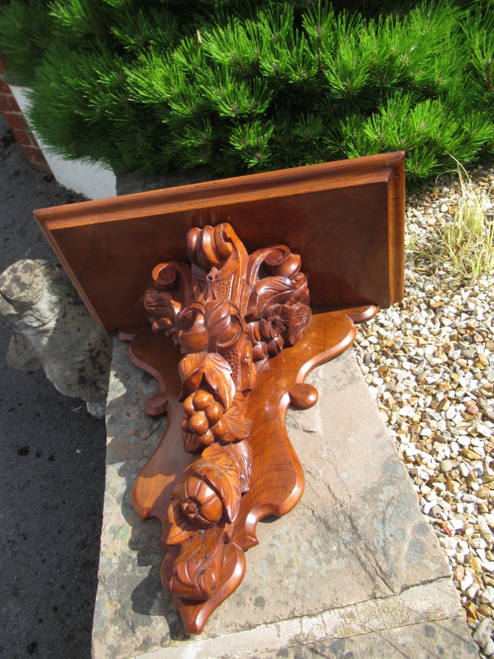 A carved Victorian walnut wall bracket featuring a flat top ledge supported by an ornate central motif of carved leaves, fruit, and scrollwork on a shaped backplate. View IX