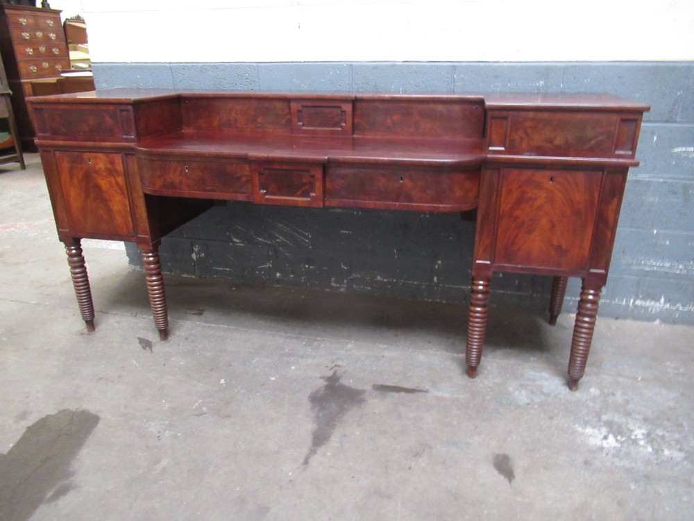 An early 19th century Scottish mahogany sideboard featuring a raised stage back, pedestal cupboards, central drawers, and spiral turned legs. View II