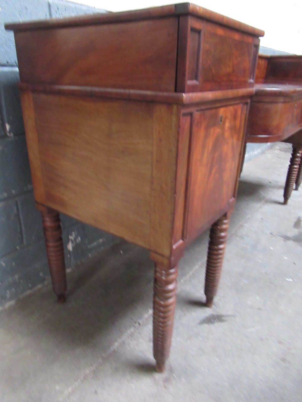 An early 19th century Scottish mahogany sideboard featuring a raised stage back, pedestal cupboards, central drawers, and spiral turned legs. View IV