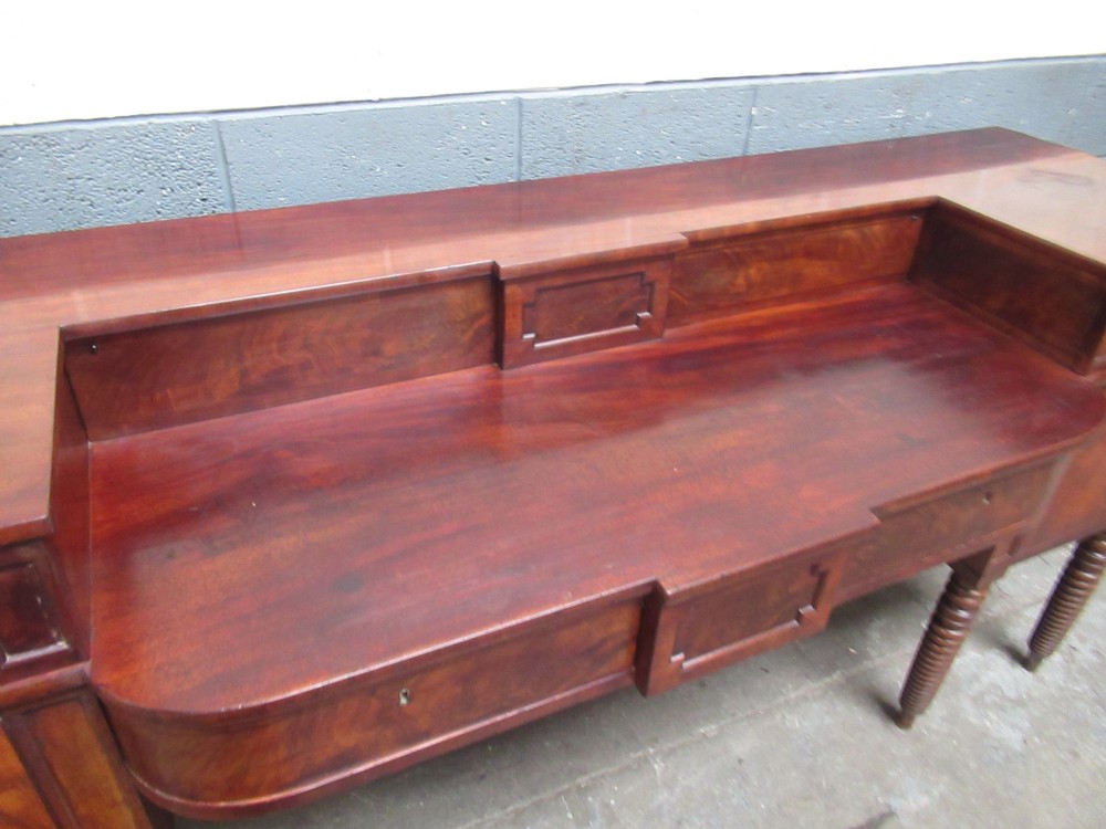 An early 19th century Scottish mahogany sideboard featuring a raised stage back, pedestal cupboards, central drawers, and spiral turned legs. View VI
