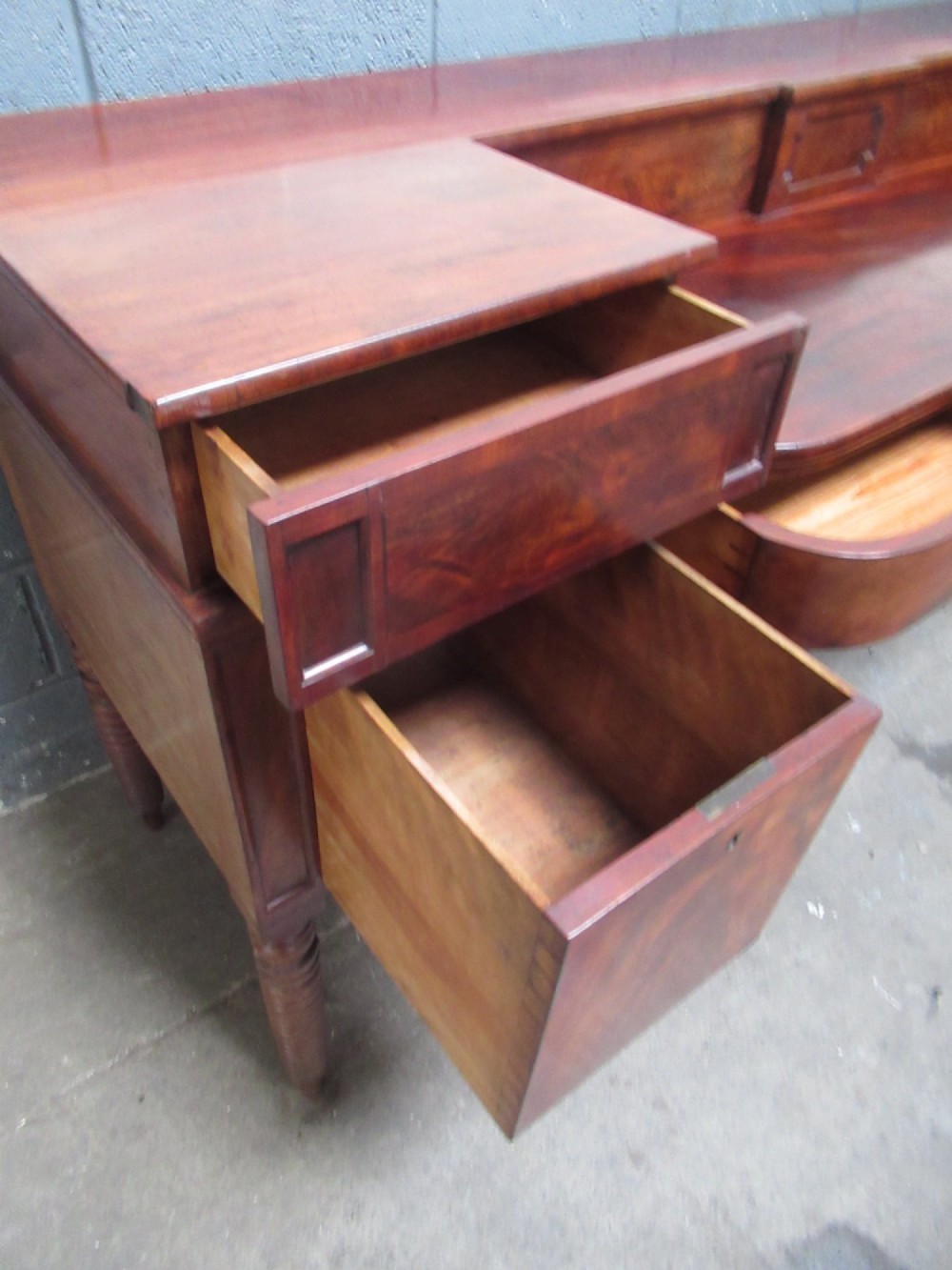 An early 19th century Scottish mahogany sideboard featuring a raised stage back, pedestal cupboards, central drawers, and spiral turned legs. View X