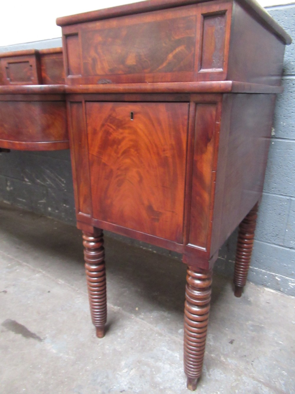 An early 19th century Scottish mahogany sideboard featuring a raised stage back, pedestal cupboards, central drawers, and spiral turned legs. View XIII