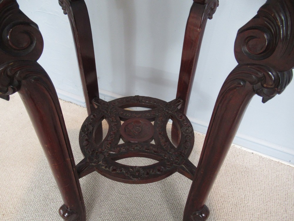 A tall carved dark hardwood stand featuring an inset rectangular pink marble top, ornate pierced apron, and a carved lower shelf. View II